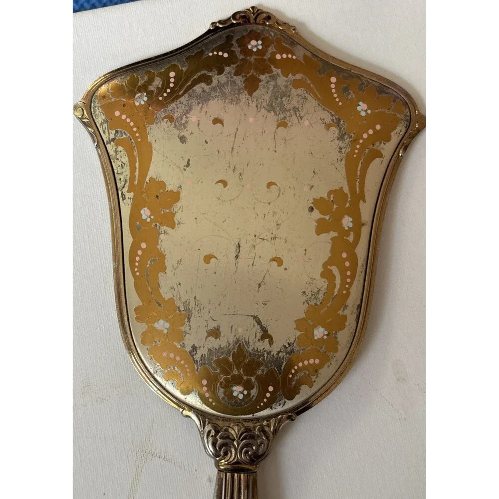 Vintage or antique gold-tone handheld vanity mirror.